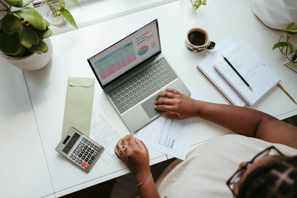 Person comparing documents while working on a laptop